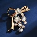 Close-up of golden bow brooch with sparkling rhinestones on dark blue background - Ribbon Bowknot