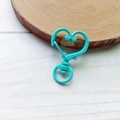 Close-up of tiffany blue heart-shaped alloy lobster clasp on a round wooden base - Lake Blue