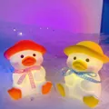 Dual pack of duck night lights with red and yellow hats glowing on purple mesh background - Chubby Duck Orange