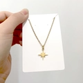 Detailed view of a gold starburst pendant necklace held on a minimalist white card display - DN109 North Star