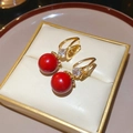 Close-up of red zircon earrings in a beige gift box with polished gold finish detail - Ear Buckle Round Bead Style (WE5727)