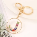 Detailed shot of golden alphabet J keychain with colorful rhinestones on a white plate - Letter J