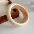 Detail eines klobigen cremefarbenen Harzarmreifs mit Marmortextur auf einer Samtbox - Unregelmäßig / Creme