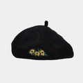 Detail shot of black wool beret featuring three yellow sunflower embroidery accents - Black