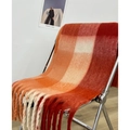 Orange and red checkered cashmere scarf with tassels draped on a metal chair - Orange Red