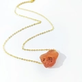 Detailed close-up of a natural orange raw stone pendant with a delicate gold chain - Red Agate