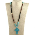 Detail van 8mm turquoise geknoopte kralenketting met een grote turquoise kruishanger - Zwart