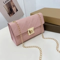 Pink quilted shoulder bag with gold chain strap and square lock closure on white table - Pink