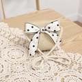 Detail of straw crossbody bag with white polka dot bow on a lace tablecloth - Beige Bag