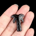 Black natural stone coconut tree pendant held by hand for DIY jewelry necklaces - Obsidian