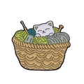 Cartoon white cat enamel pin in a brown basket with green and teal yarn balls - Cat in Yarn Basket