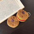 Handmade wool felt burger keychain charm with smiling face detail on a book background - Mini Burger