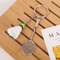 Detailed close-up of a silver badminton racket and shuttlecock keychain on a wooden tray - Racket With Clasp / White (Green Head)