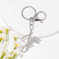 Detail von silbernem Buchstabe J Schlüsselanhänger mit Strass und Feenflügeln - Stil J / Silber
