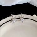 Detailopname van zilveren ster oorbellen met zirkonia kristallen op witte zijden stof - S925 Zilveren Pin / Zilver