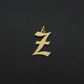 Macro detail of golden metal Z letter pendant with small hoop on dark textured background - Letter Z