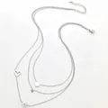 Dettaglio della collana a tre strati in acciaio inossidabile 18k con perla e cuori - Oro 18K