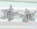 Orecchini a fiore in argento con zirconi scintillanti su un supporto bianco minimalista - Argento