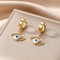 Detailed close-up of golden Evil Eye drop earrings with blue inlay on silk background - White Inner Eyelash Eye