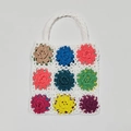 Nahaufnahme einer handgehäkelten Tragetasche mit bunten Granny-Square-Blumenmustern - Weiß