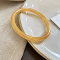 Macro shot of translucent yellow resin bangle with amber texture on white plate - Orange