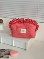 Berry red checkered makeup bag with ruffled edges on a white shelf with accessories - Ruffle Bag / Berry Red Plaid