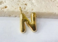 Macro view of gold bubble letter N pendant with high-gloss finish and puffy design - Letter-N / Gold