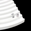 Detailed close-up of silver snake and flower stud earrings on a wavy display stand - Snake