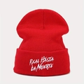 Detailed close-up of white Real Hasta La Muerte embroidery on a red ribbed knit beanie - Red White Text