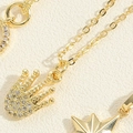 Dettaglio macro di ciondoli a corona e stella placcati in oro con zirconi lucidi - Collana Palmo con Corona