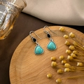 Close-up of heart-shaped turquoise earrings with silver hooks on a wooden display - E5852-Heart Turquoise Black Water Drop