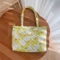 Detailed shot of green quilted cotton tote bag with cartoon goose prints on a wooden table - Duck