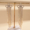 Detailansicht langer goldener Quastenohrringe mit funkelnden Strasssteinen auf Metallständer - S925 Silbernadel Lange Quaste Stil / Gold