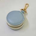 Close-up of mini round blue leather jewelry case with gold metal carabiner and white zipper - 5*5*3cm / Blue