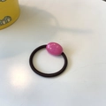 Detailed shot of elastic black hair tie with a pink oval resin bead on a white surface - Rose Pink