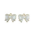 Detailed macro view of two white enamel bow pendants with gold metal edges for DIY jewelry - White
