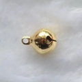 Accesorio de cascabel de metal dorado pulido sobre una superficie de felpa blanca - Cobre / 12mm