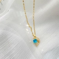 Détail macro du collier pendentif dauphin doré avec pierre bleue sur tulle blanc - Dauphin