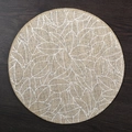 Round natural jute placemat featuring white leaf pattern on a dark wood table - 38cm / Lush Branches and Leaves