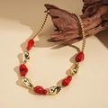 Detail of red and gold acrylic beads on wood, showcasing chunky bohemian necklace texture - Red