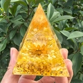 Main tenant une pyramide en cristal doré avec résine, pierres jaunes et fleur de lotus - Style 62