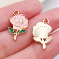 Pink and green enamel rose pendants with rhinestone centers shown on a finger - Pink Rhinestone Rose (16691)