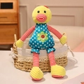 Cute plush cartoon duck toy with blue polka dot dress and striped limbs in a woven basket - Little Duck