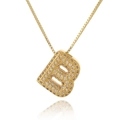 Macro detail of gold letter B pendant with micro-paved cubic zirconia and box chain - Letter B