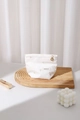 Detail of white striped makeup bag with gold flower zipper pull and embroidered heart - Small / White