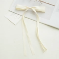 Detail showing elegant cream satin bow hair clip with long flowing ribbon streamers - Champagne