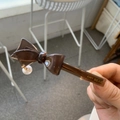 Detail of a brown acetate bow hair clip with gold lettering and a hanging white pearl - Chocolate Bow