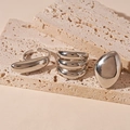 Dettaglio di anelli geometrici in argento lucido esposti su base in pietra di travertino - Argento - Stile Geometrico (Set da 3 pezzi)