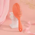 Orangene hohle Haarbürste für Massage von nassem und trockenem Haar auf Seidenhintergrund - Orange