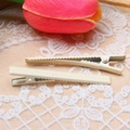 Close-up of two cream-colored 6cm slim duckbill metal hair clips on white floral lace fabric - Off White